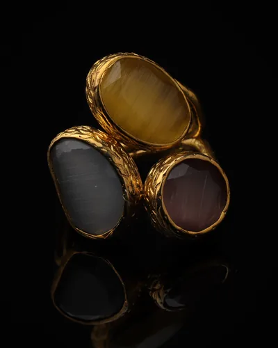 Linen & Marigold - a gold-plated ring with three yellow and cream cat eye stones, on black
