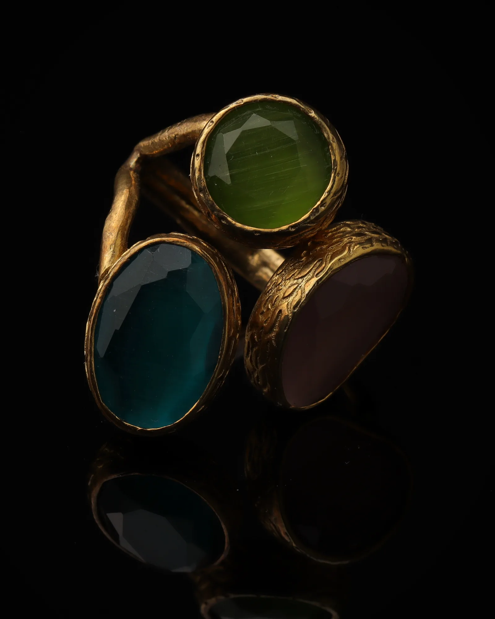Aqua & Damson - a gold-plated ring with three teal and plum cat eye stones, on black