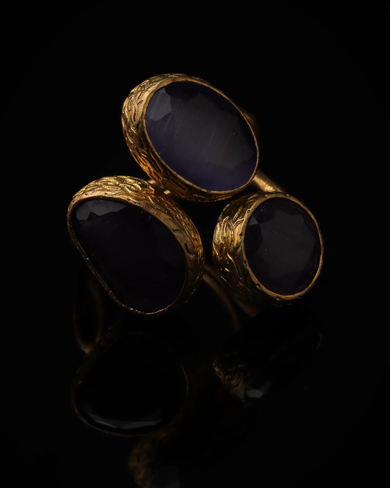 Iris - a gold-plated ring with three purple and violet cat eye stones, on black