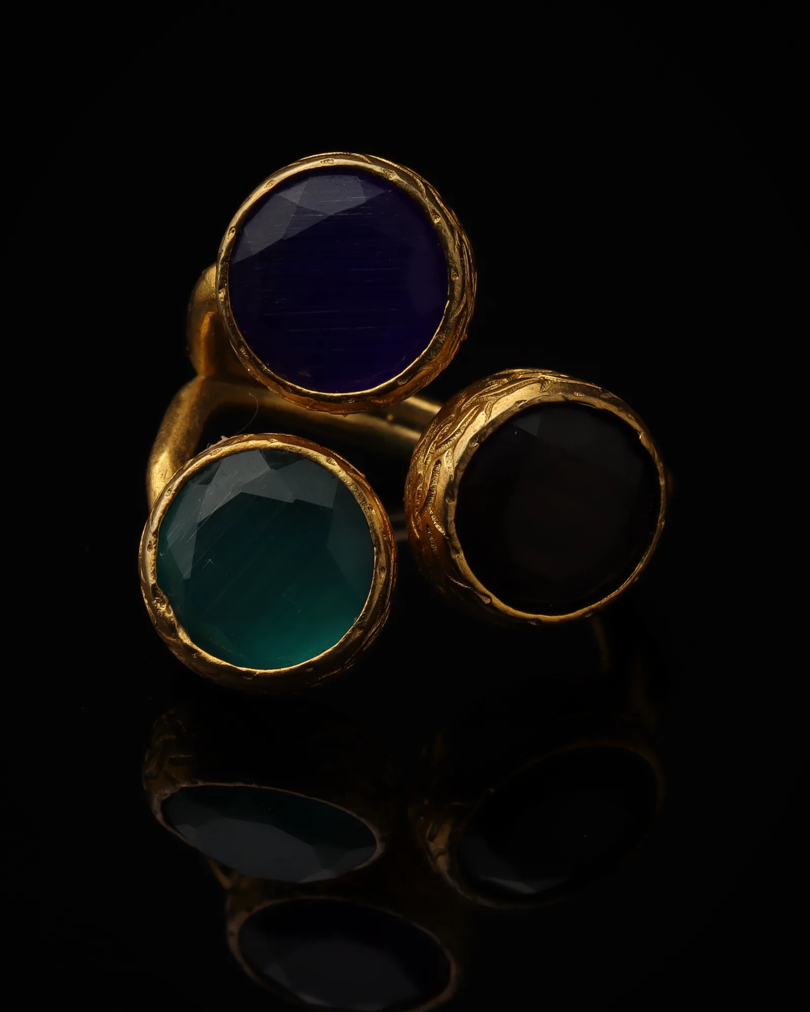 Delft & Juniper - a gold-plated ring with three blue and green cat eye stones, on black