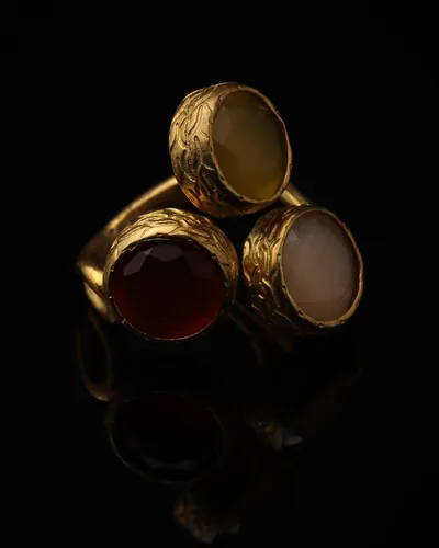 Claret & Chalk - a gold-plated ring with three red and cream cat eye stones, on black