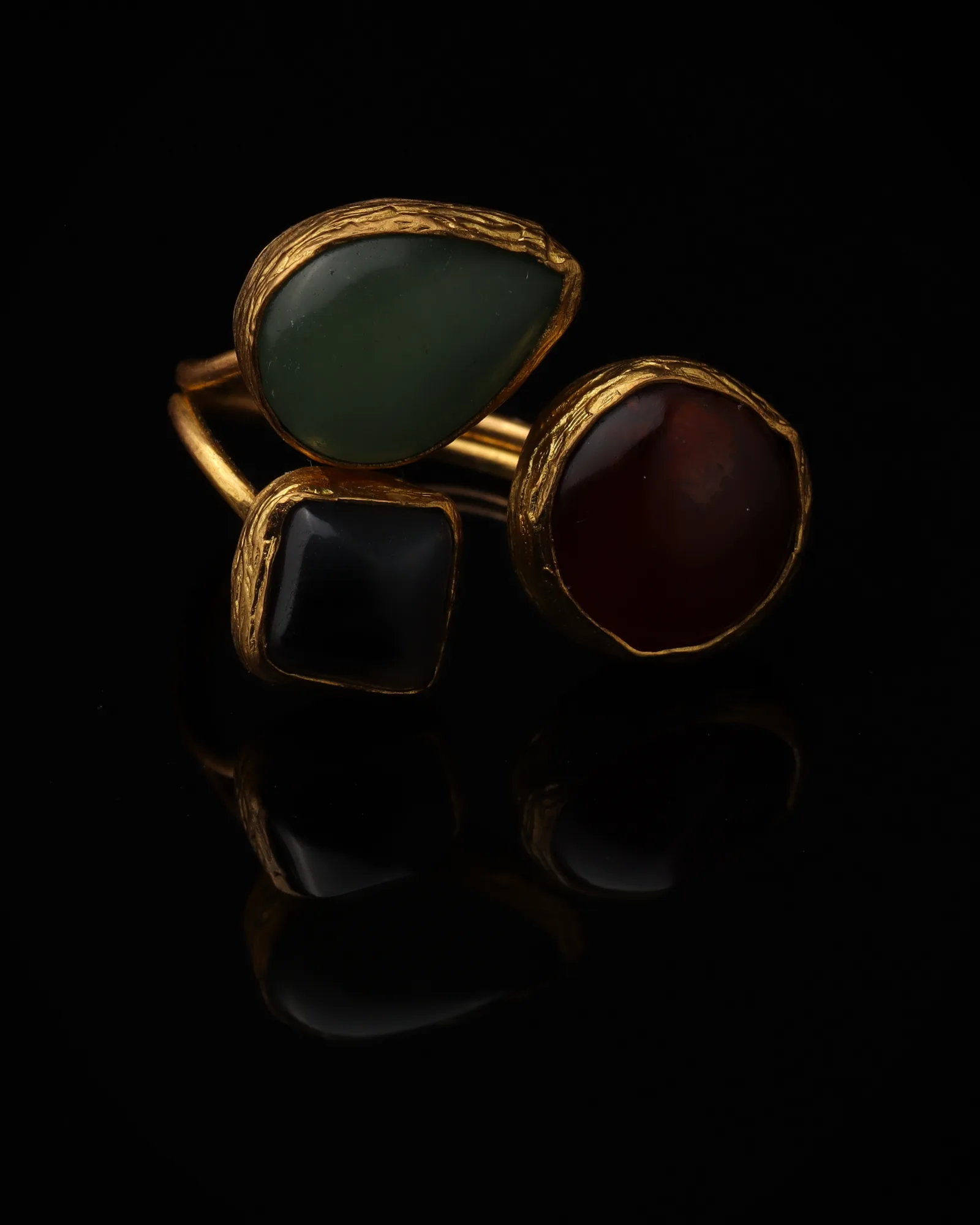 Celadon & Port - a gold-plated ring with three sage green and red cat eye stones, on black