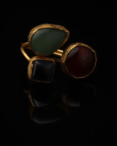 Celadon & Port - a gold-plated ring with three sage green and red cat eye stones, on black