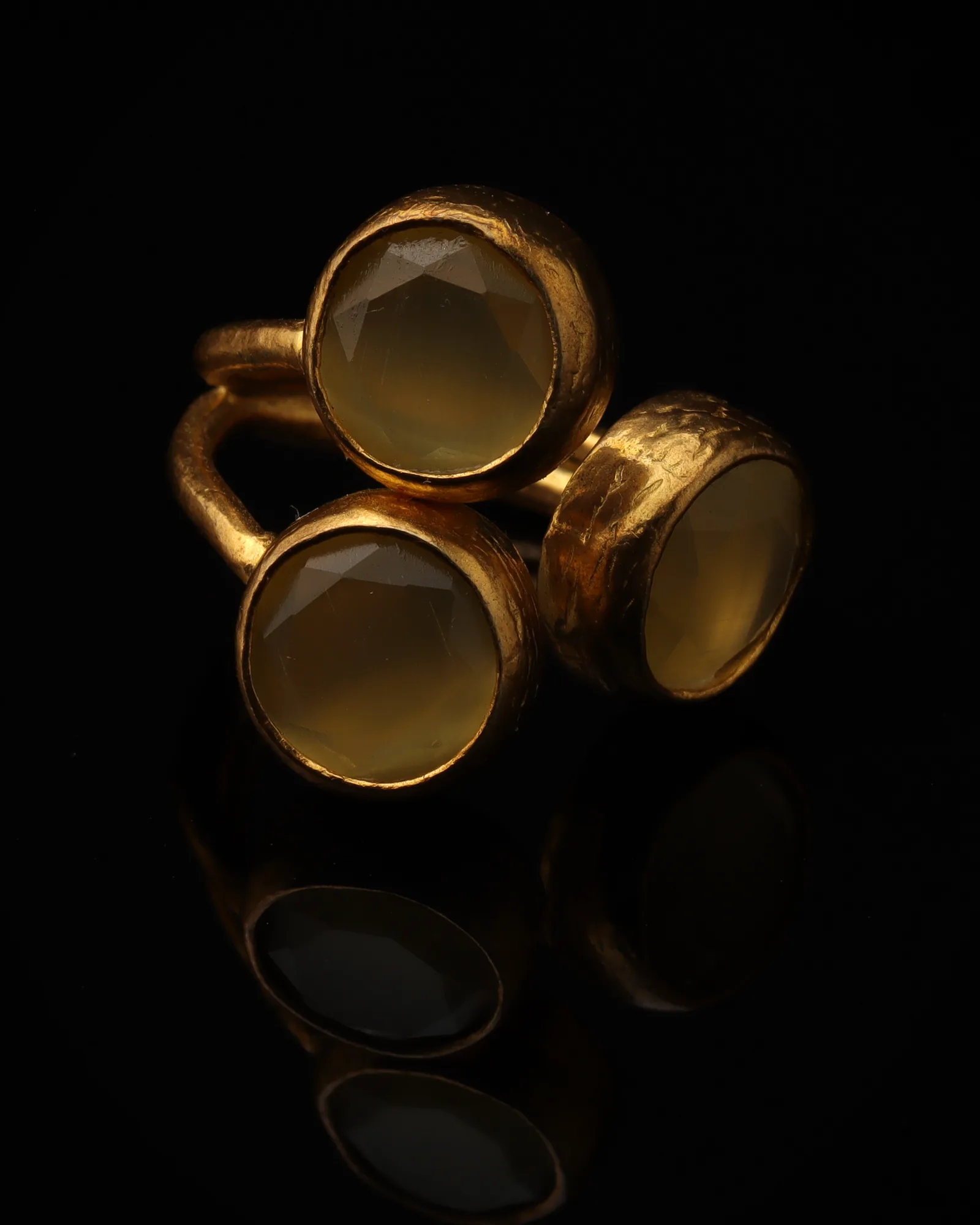 Ochre - a gold-plated ring with three yellow and brown cat eye stones, on black