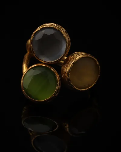 Dove & Basil - a gold-plated ring with three grey and green cat eye stones, on black