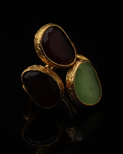 Burgundy & Pistachio - a gold-plated ring with three red and green cat eye stones, on black