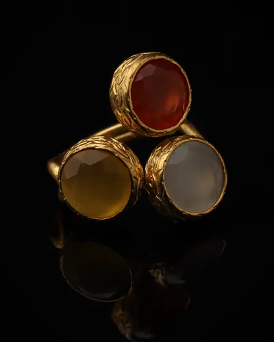 Cinnamon & Custard - a gold-plated ring with three red and yellow cat eye stones, on black