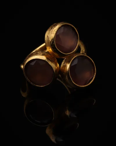 Rosewood & Ash - a gold-plated ring with three pink and brown cat eye stones, on black