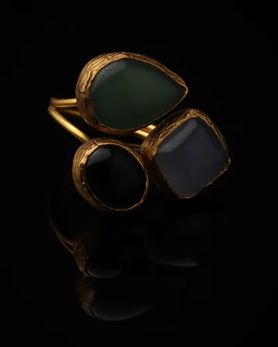 Cypress & Ink - a gold-plated ring with three green and navy cat eye stones, on black