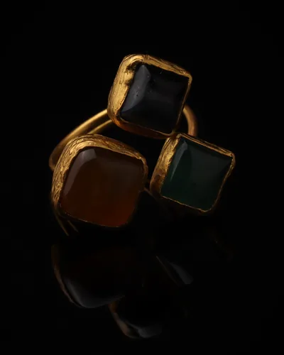 Ginger & Ivy - a gold-plated ring with three orange and green cat eye stones, on black