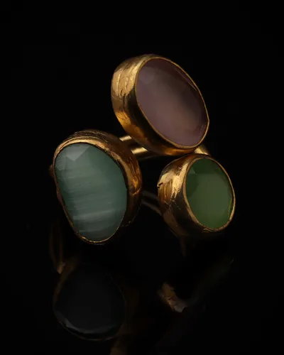 Rosewater & Mint - a gold-plated ring with three pink and sage green cat eye stones, on black
