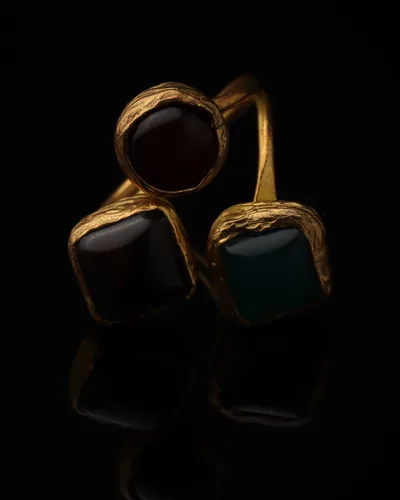 Port & Tide - a gold-plated ring with three red and teal cat eye stones, on black