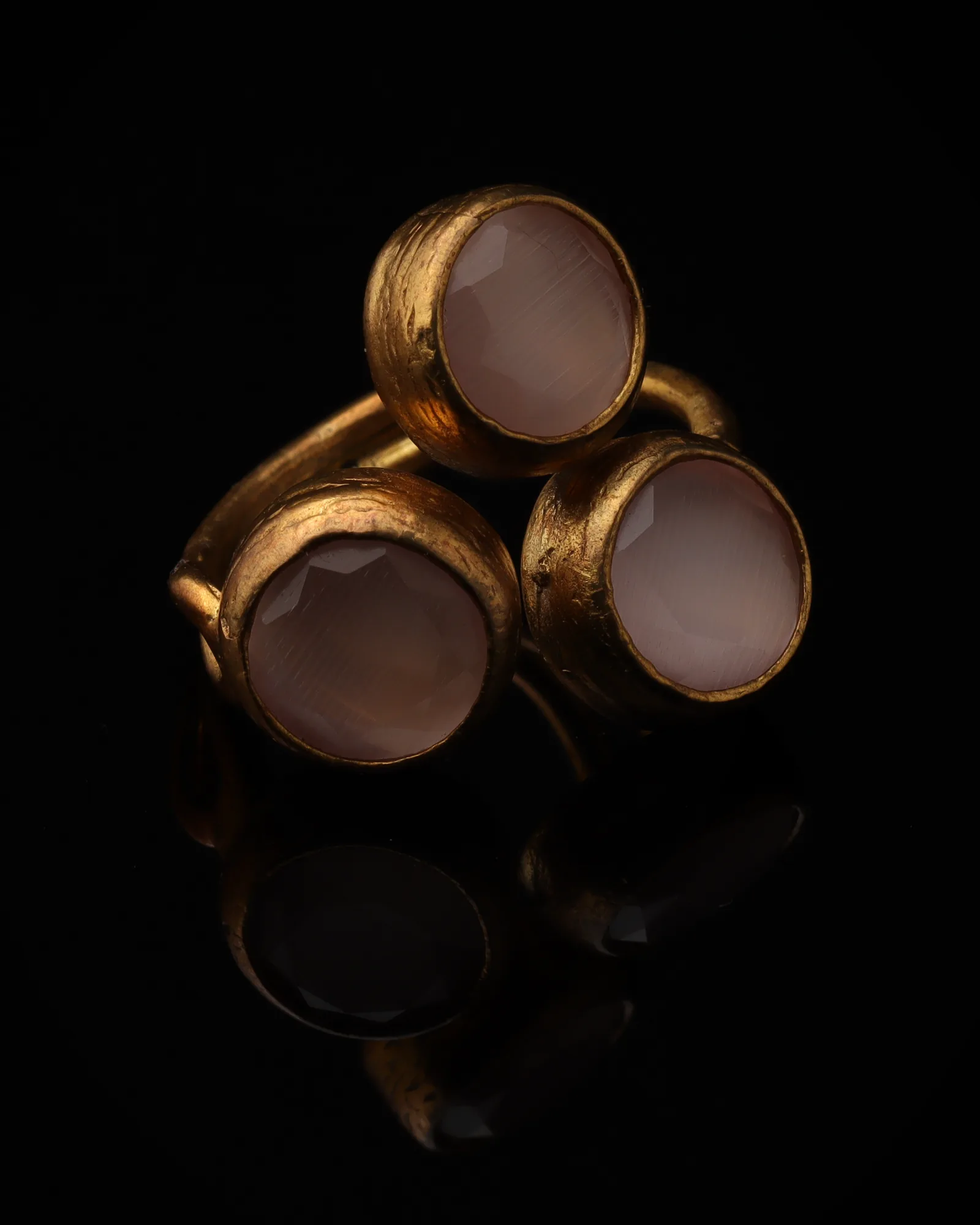 Petal - a gold-plated ring with three pink and cream cat eye stones, on black