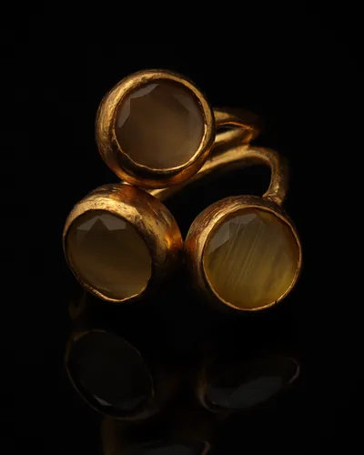 Honeycomb - a gold-plated ring with three yellow and brown cat eye stones, on black
