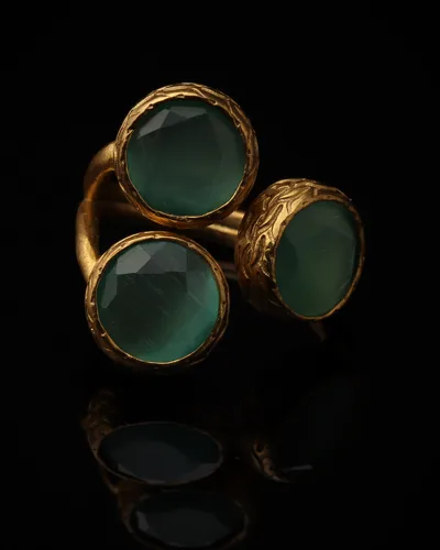 Verdigris - a gold-plated ring with three green and teal cat eye stones, on black