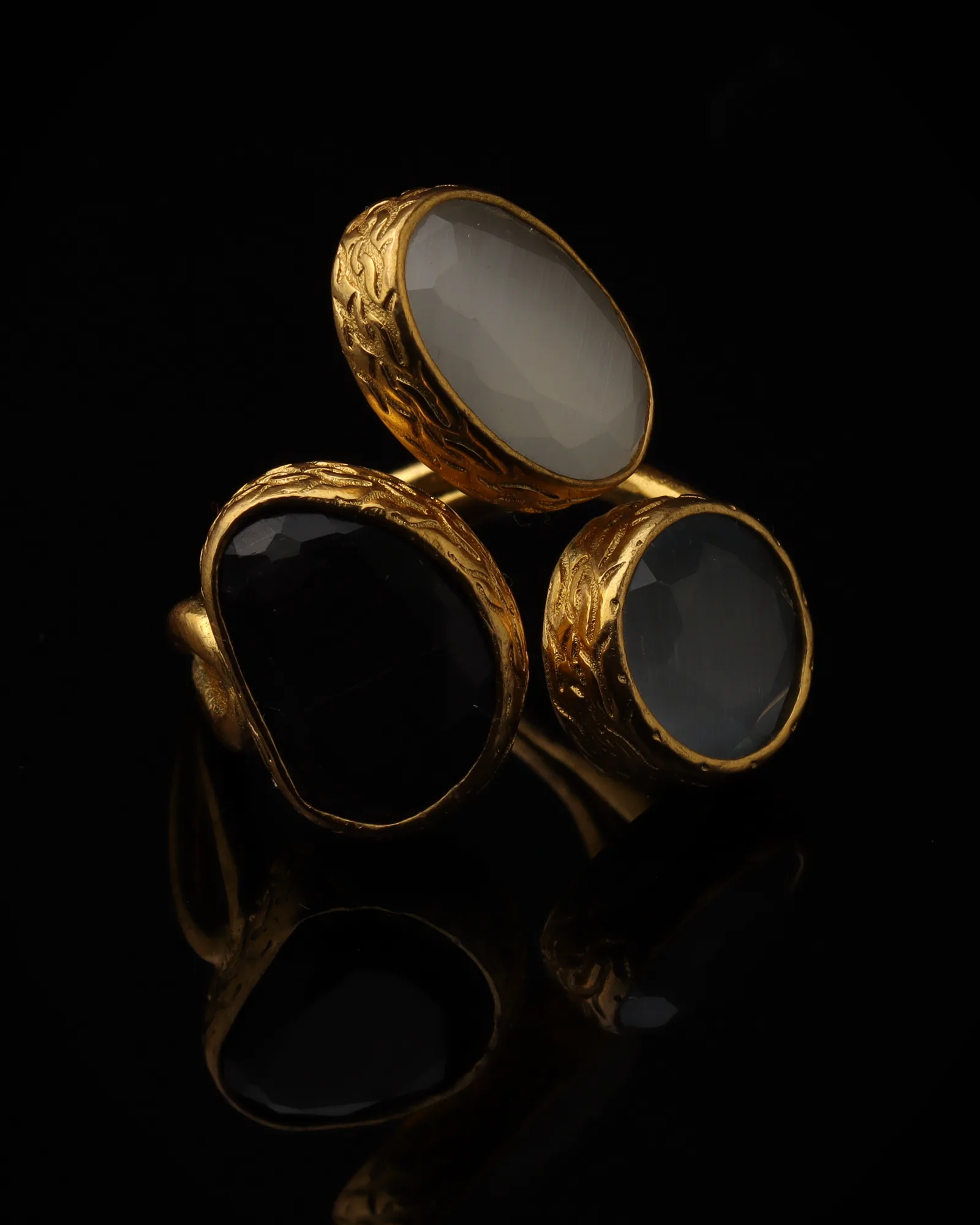 Frost & Coal - a gold-plated ring with three cream and black cat eye stones, on black