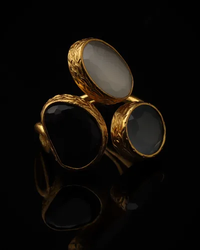 Frost & Coal - a gold-plated ring with three cream and black cat eye stones, on black