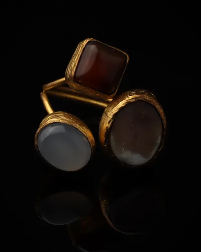 Copper & Mist - a gold-plated ring with three red and grey cat eye stones, on black