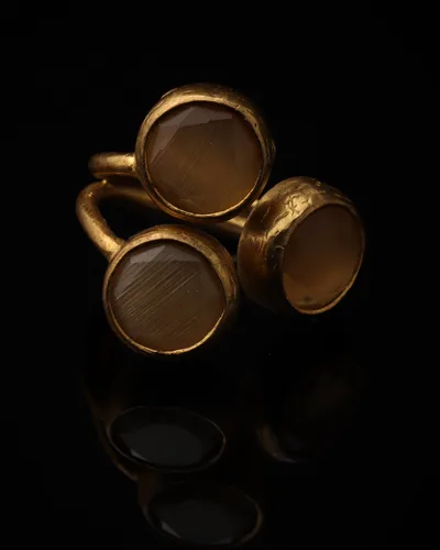 Camel & Shell - a gold-plated ring with three brown and cream cat eye stones, on black