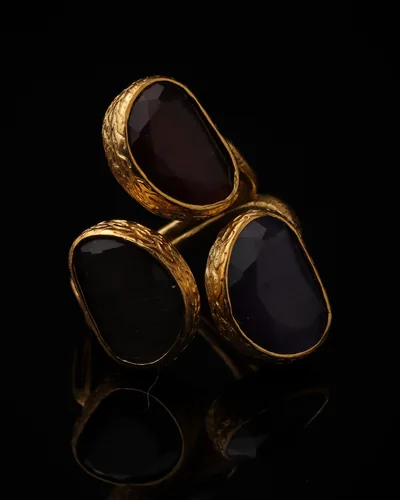 Aubergine & Thistle - a gold-plated ring with three plum and purple cat eye stones, on black