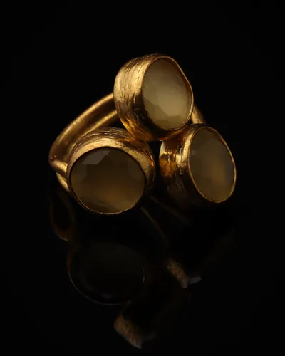 Custard & Milk - a gold-plated ring with three yellow and cream cat eye stones, on black