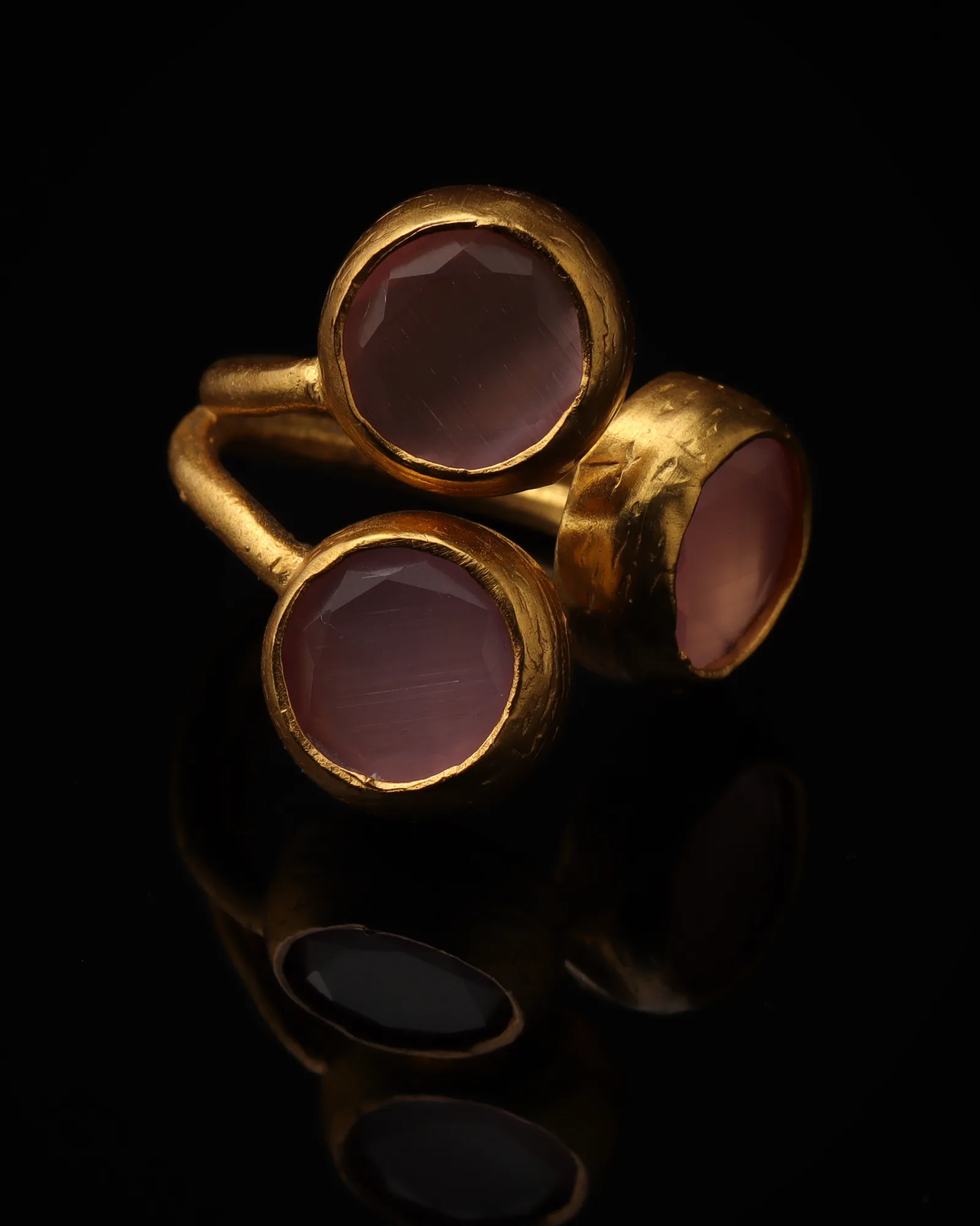 Orchid & Wisteria - a gold-plated ring with three pink and purple cat eye stones, on black