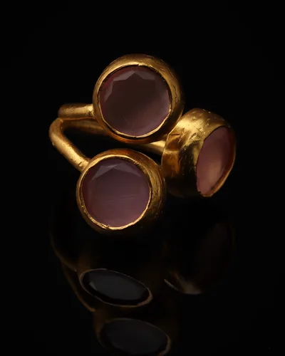 Orchid & Wisteria - a gold-plated ring with three pink and purple cat eye stones, on black