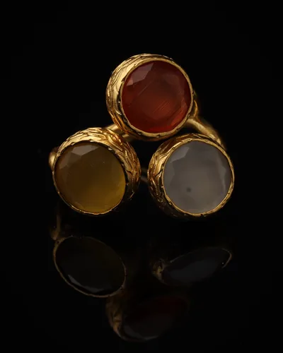 Persimmon & Cream - a gold-plated ring with three red and cream cat eye stones, on black