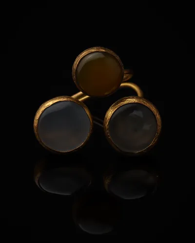 Mist & Dune - a gold-plated ring with three grey and cream cat eye stones, on black