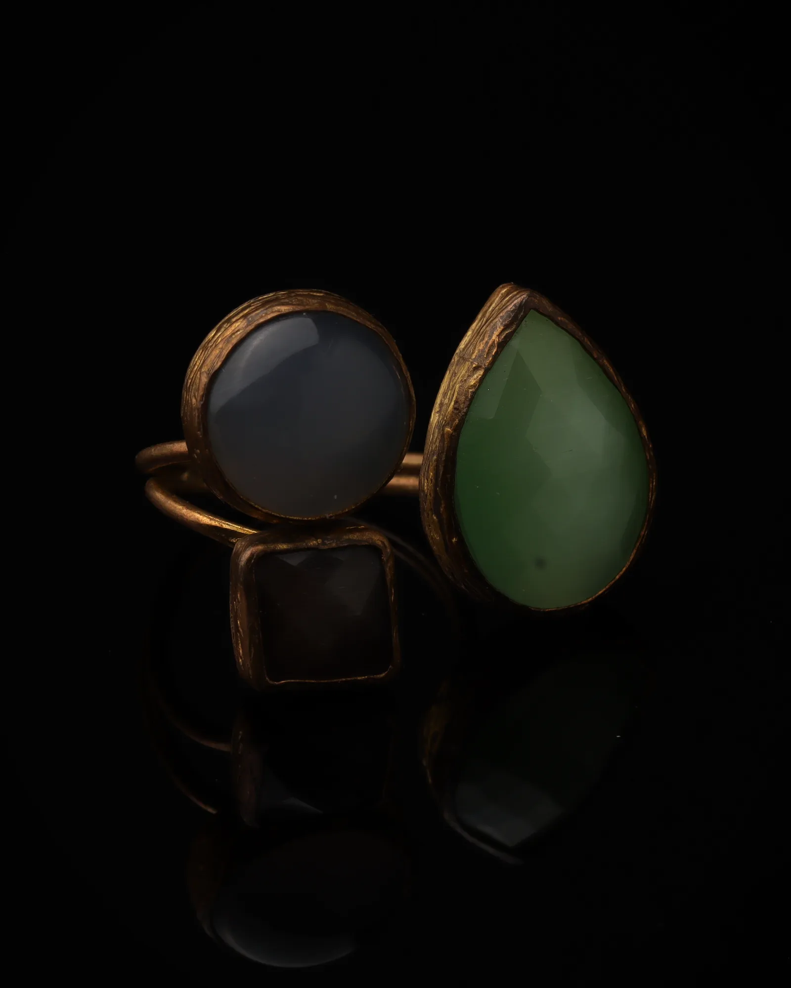 Slate & Fern - a gold-plated ring with three grey and green cat eye stones, on black